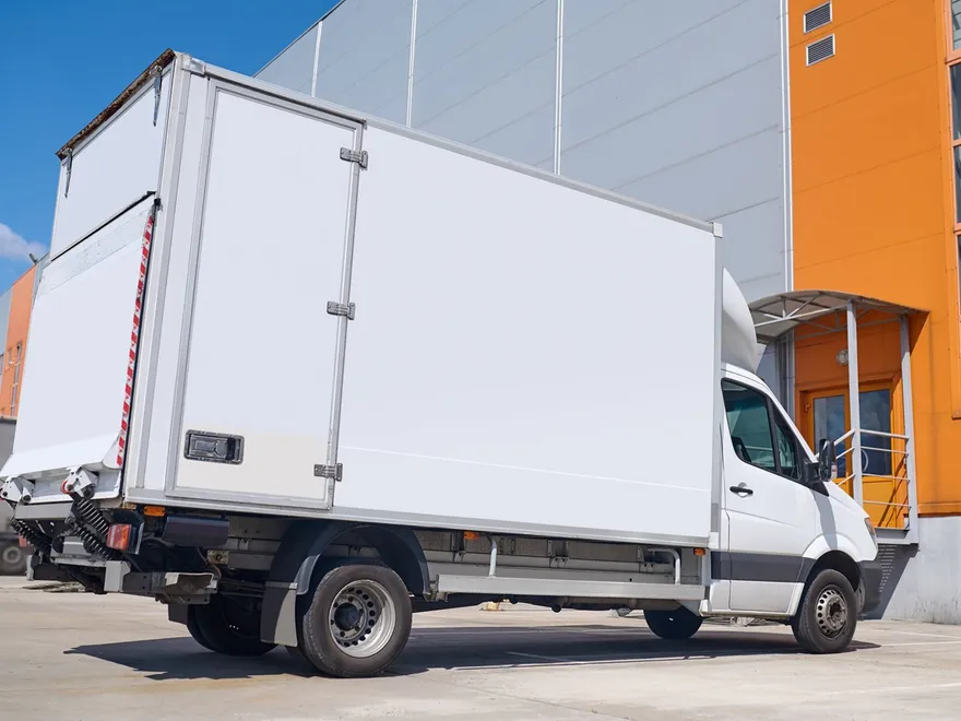 A closed removal truck parked outside a commercial building